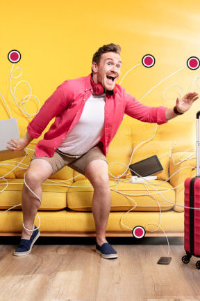 man in yellow room, reaching for his red suitcase