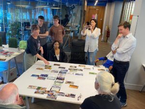 woman pointing at cards on a table while others look on